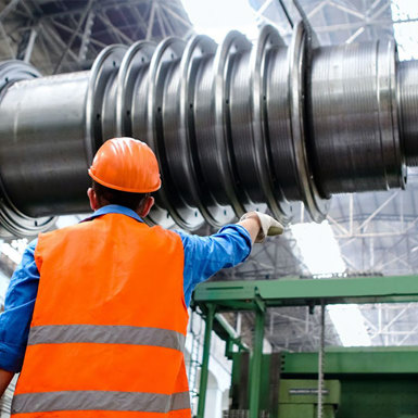A man in an orange vest stands beside a large metal machine.