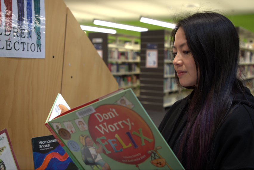 Early Childhood Education student Thuy reading children's books in the Preston campus library.