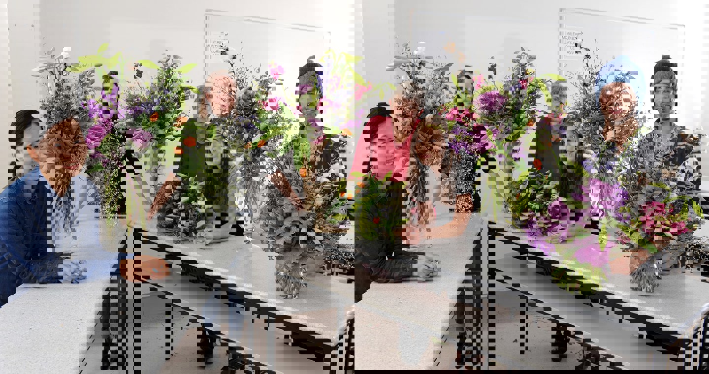 Floristry Studies students sitting at a table with their vase and bouquet floral arrangements