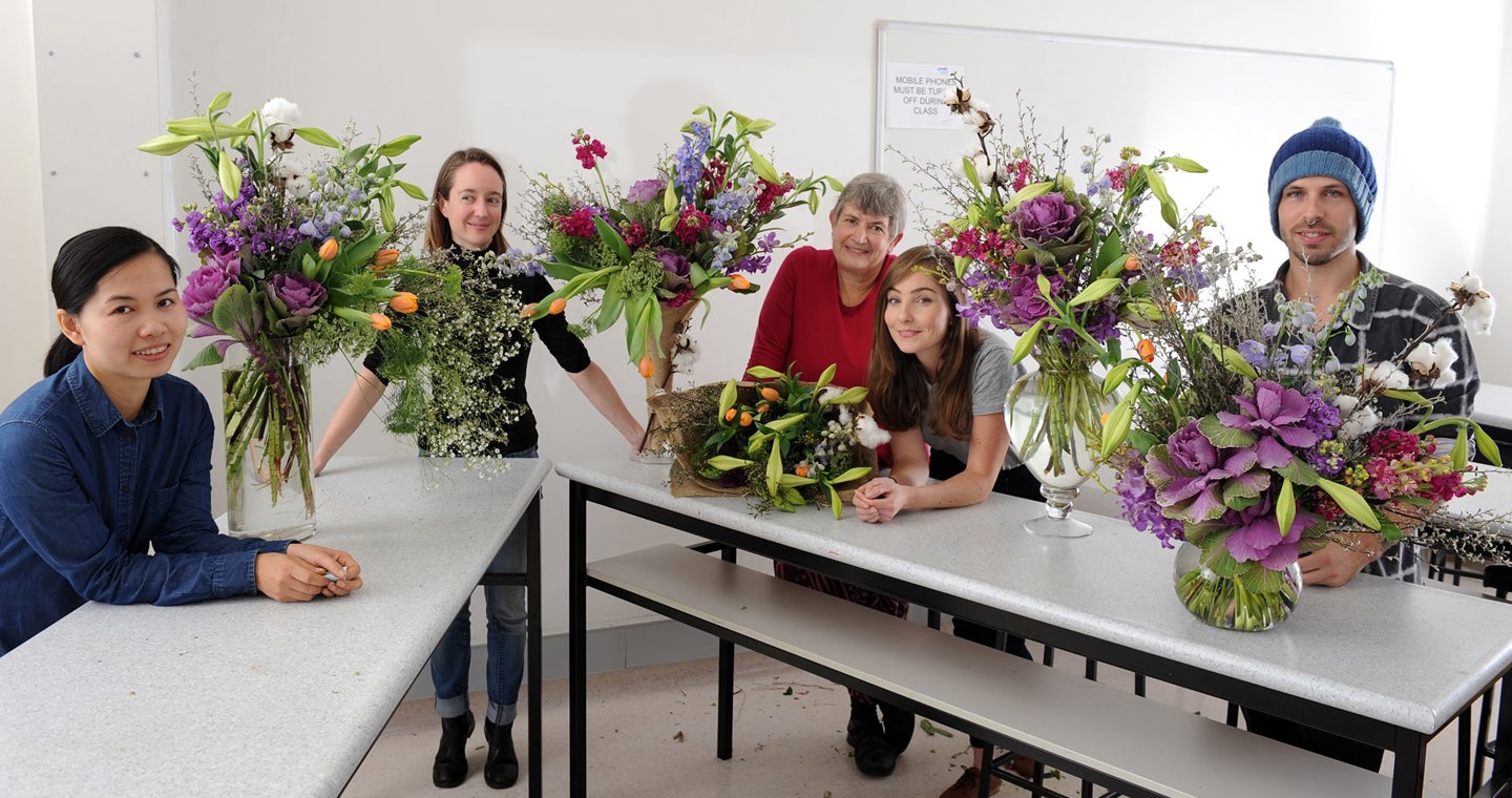 Floristry Studies students sitting at a table with their vase and bouquet floral arrangements