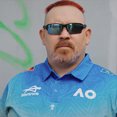 Red-haired man wearing sunglasses and a blue shirt