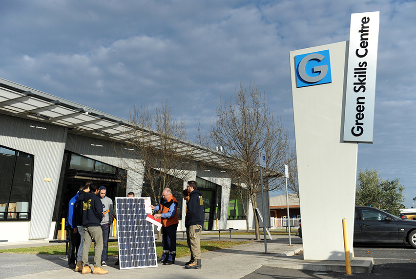 Students and an instructor stand around a solar panel outside the Green Skills Centre at Melbourne Polytechnic’s Epping campus.