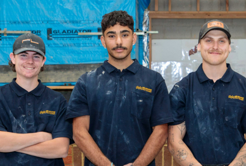 Three Bricklaying students in Melbourne Polytechnic polo tops smiling at the camera.