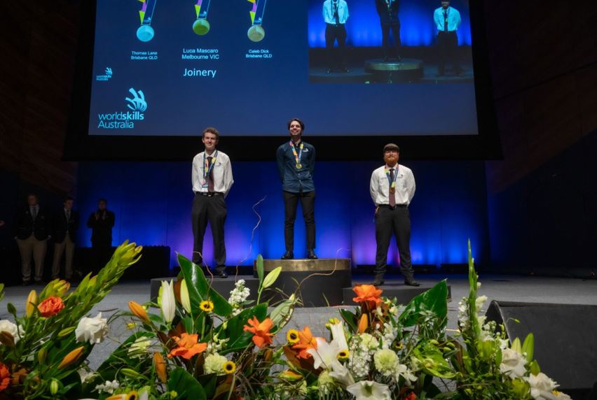 Melbourne Polytechnic student, Luca Mascaro, standing on the podium after winning the gold medal for Joinery at the WorldSkills Australia National Championships