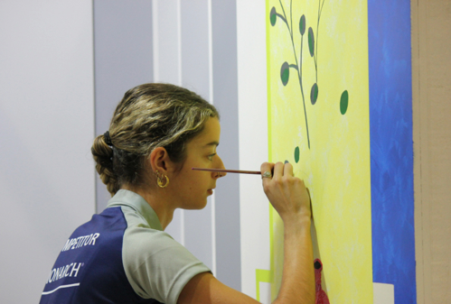 Close up of Annabelle Barrow painting a decorative element by hand on a wall for WorldSkills competition.
