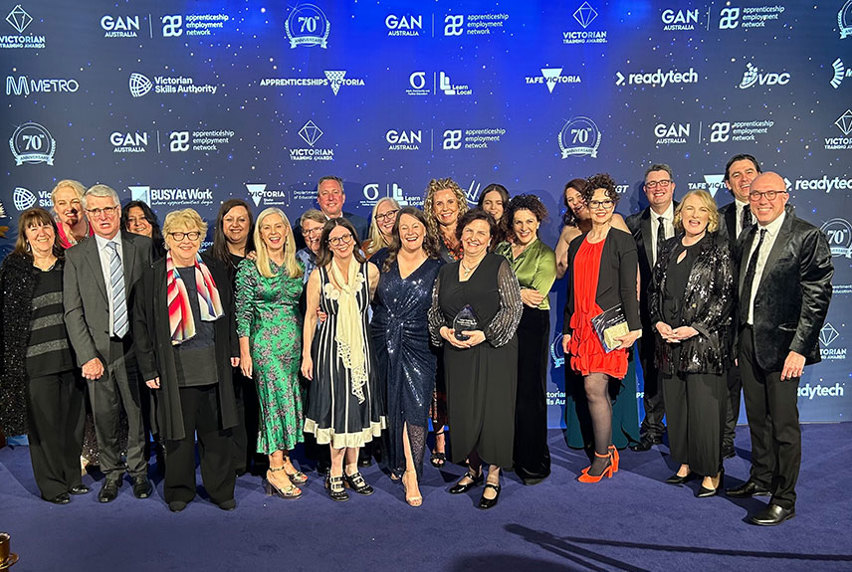 A group of professionals posing together on a blue carpet, representing award winning collaboration in an engaging environment.