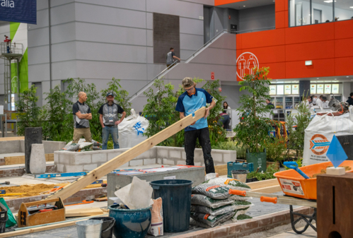 WorldSkills Landscaping Construction competition zone with competitors and official judges supervising.