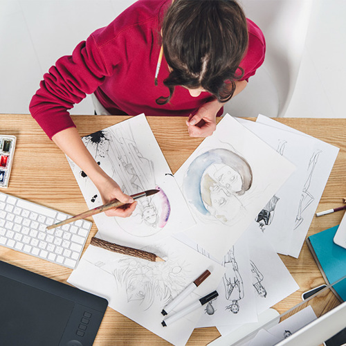 Young girl drawing by table with computer and ipad