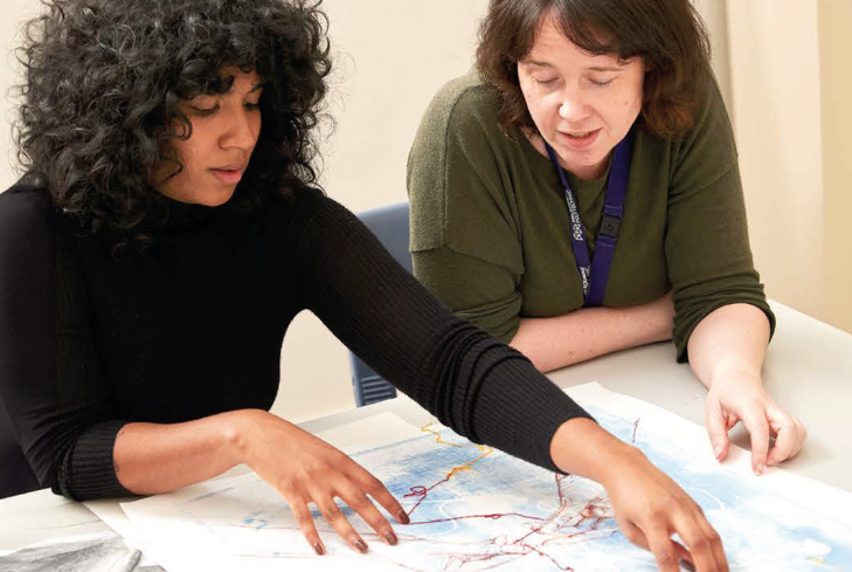 Two women sitting at a table looking at an illustration
