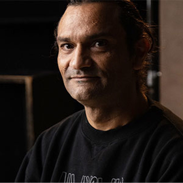 A man wearing a black t-shirt while posing for a professional photograph.