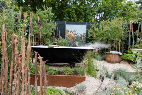 A Coastal native garden with steps, sandy base and black outdoor bathub.